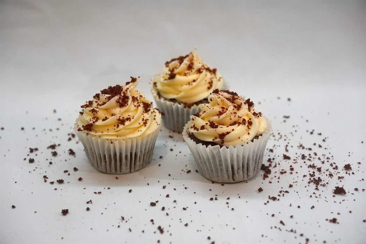 Red velvet cupcakes with cream cheese frosting and a scatter of red velvet crumb